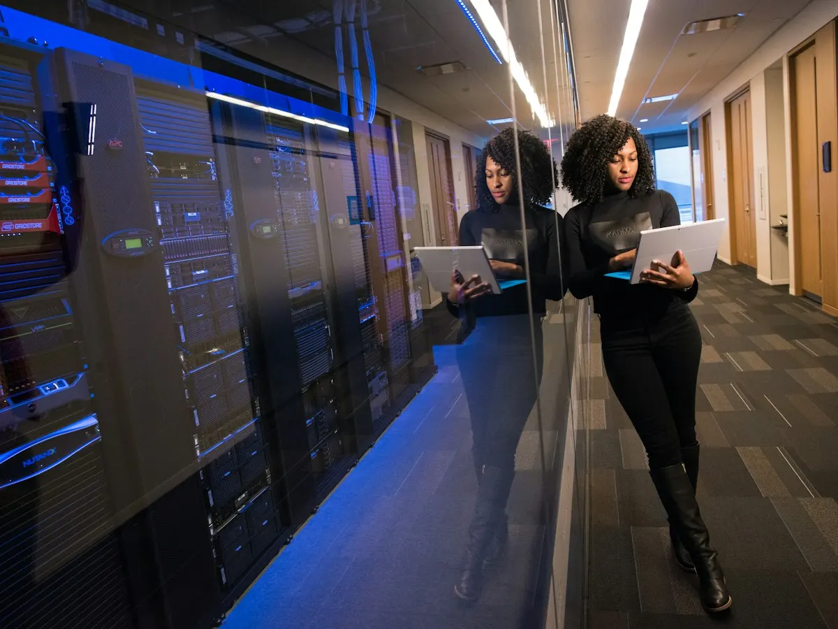 An engineer with a tablet in the corridor of a data centre, beside rows of server racks